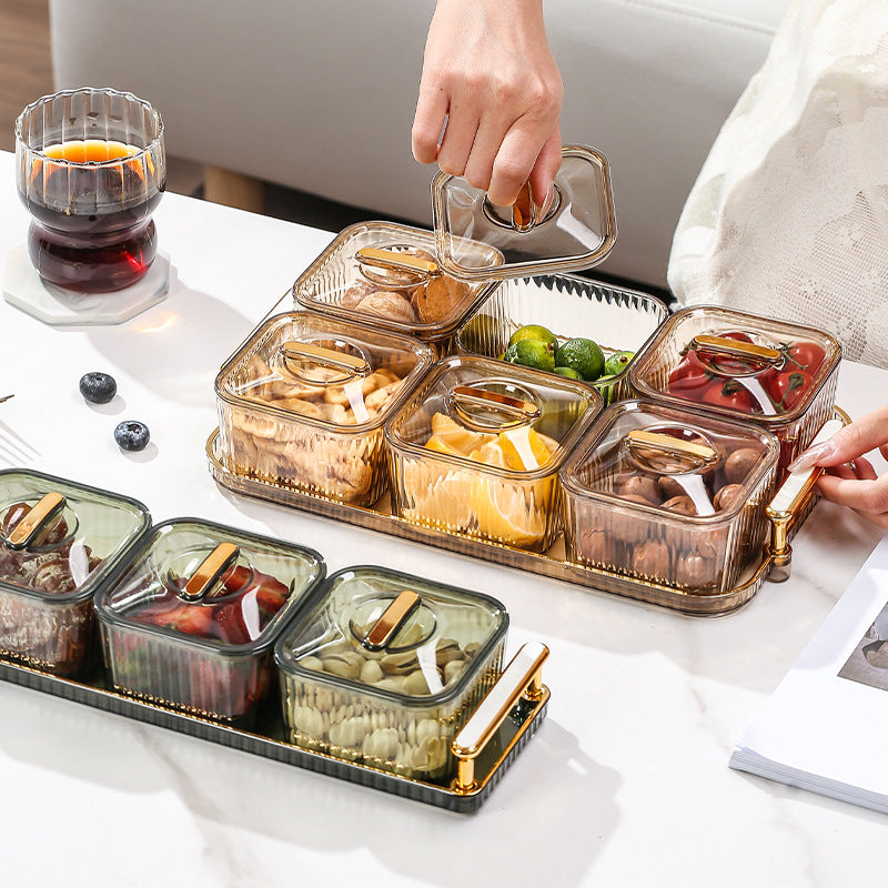 Set of glass food containers with gold accents on a tray, being used to serve snacks.