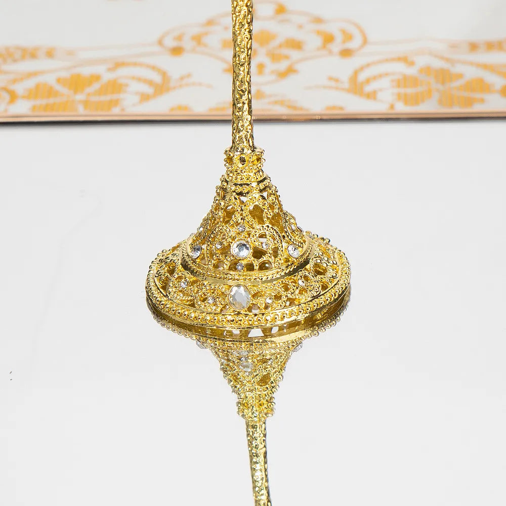 Gold decorative item with intricate design on a white background
