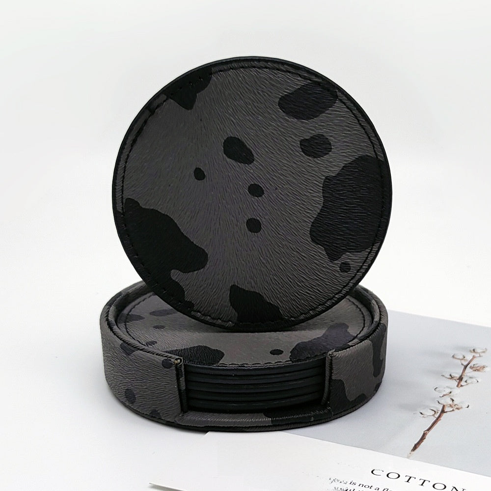 Dark cow print leather coaster, round design with black background and gray spots