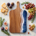 Wooden cutting board with blue resin design surrounded by fruits and cheese on a marble surface