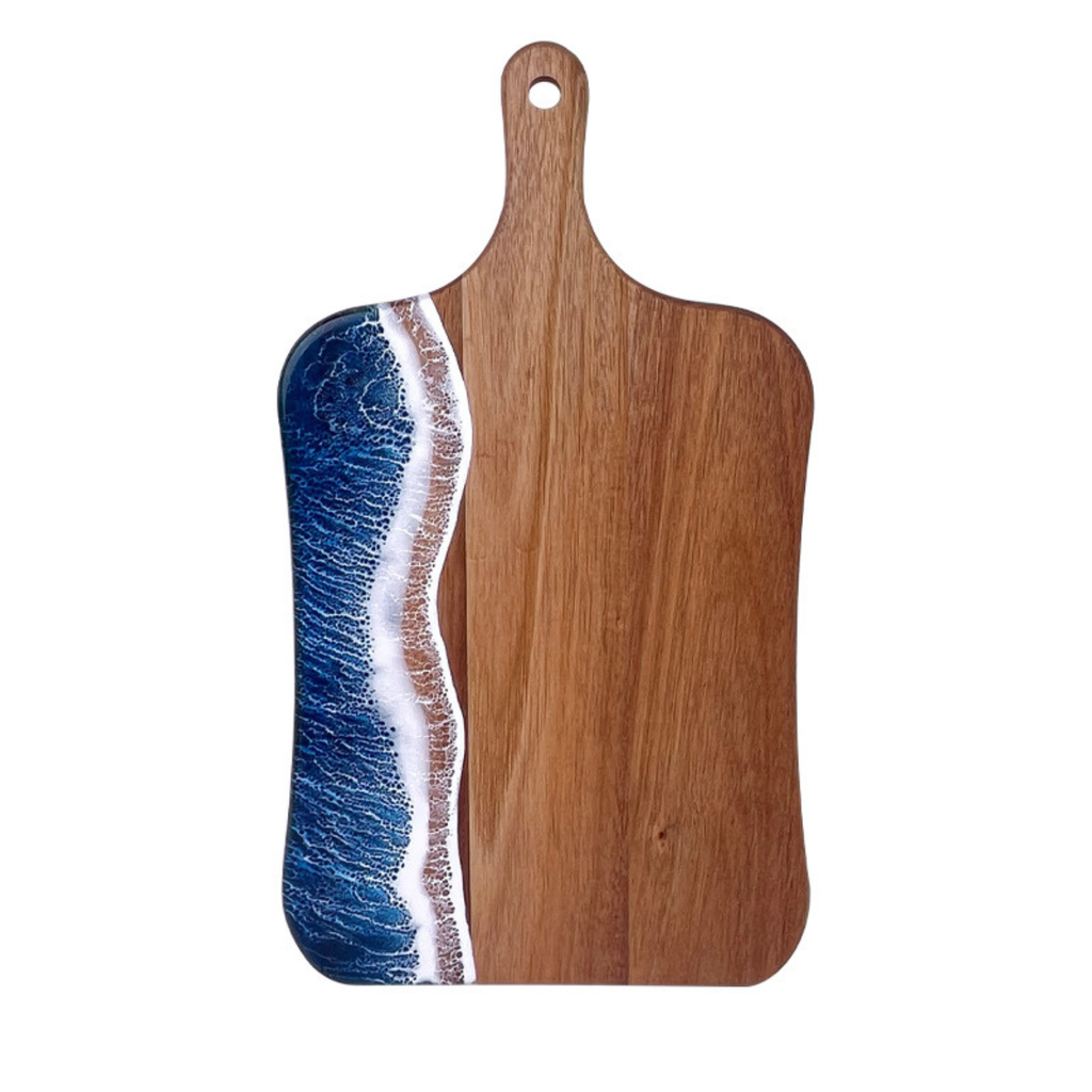 Wooden cutting board with a blue and white resin design on a white background
