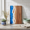 Ocean wave resin cutting board with blue epoxy and white foamy edge, wood backing