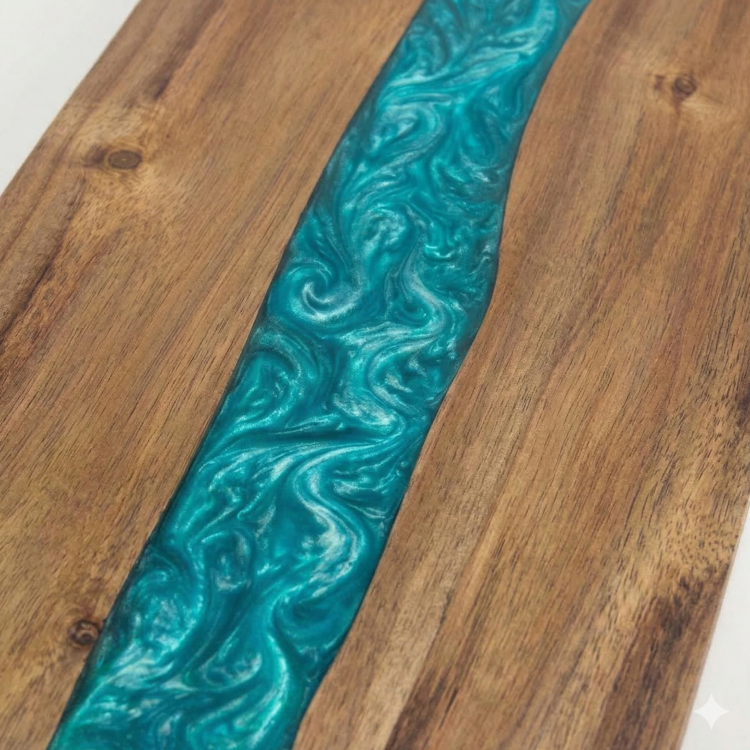 Close-up of teal epoxy river detail in an acacia wood cutting board
