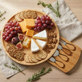 Wooden cheese board with assorted cheeses, fruits, and crackers on a wooden surface.