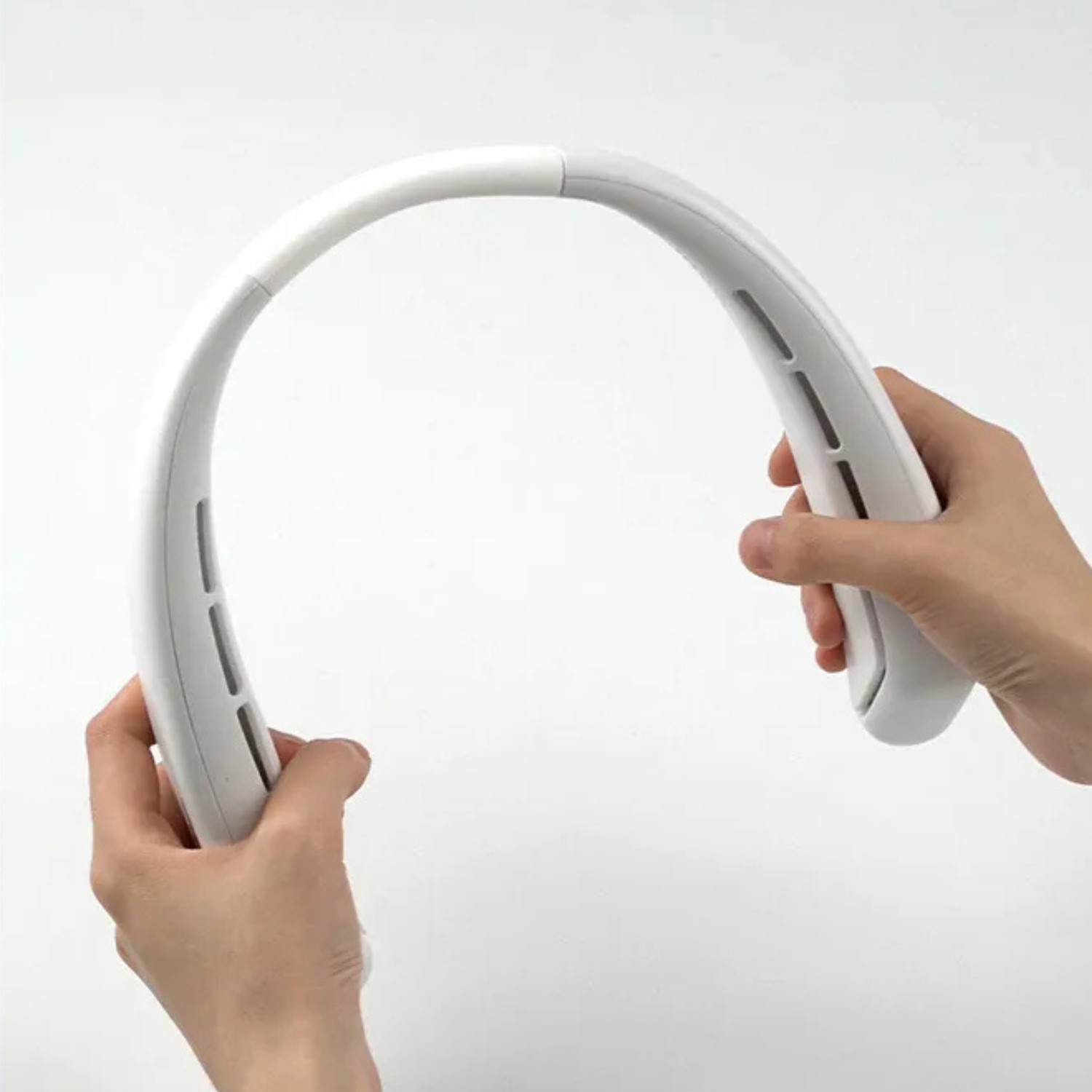 White bladeless neck fan held in hands, showing side vent openings