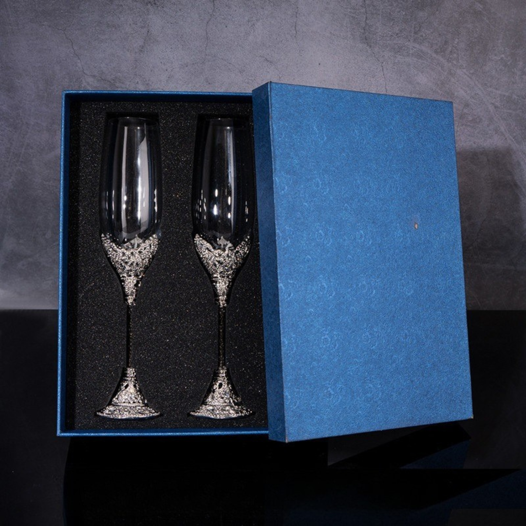 Two silver champagne flutes in a blue box on a dark background
