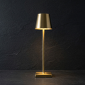 Gold LED table lamp with drum shade and square base, warm light on.
