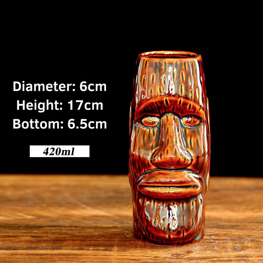 Glass tiki mug with face design on a wooden surface, showing measurements and capacity.