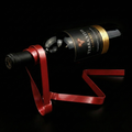 Floating wine bottle holder with red ribbon straps for a wine bottle and gold cap