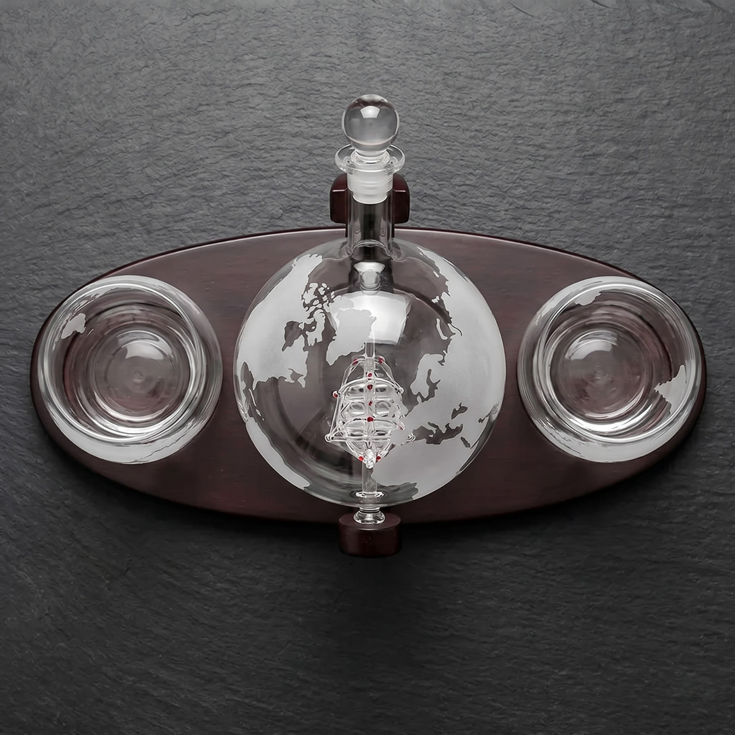 Decorative glass object with a central sphere and two side bowls on a dark background