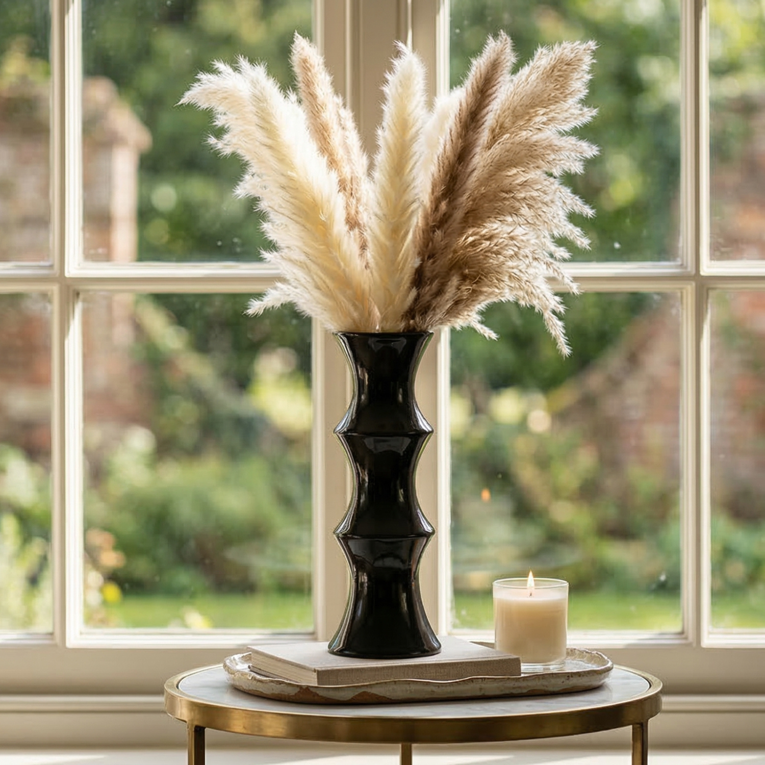 Black vase with pampas grass on a table in front of a window