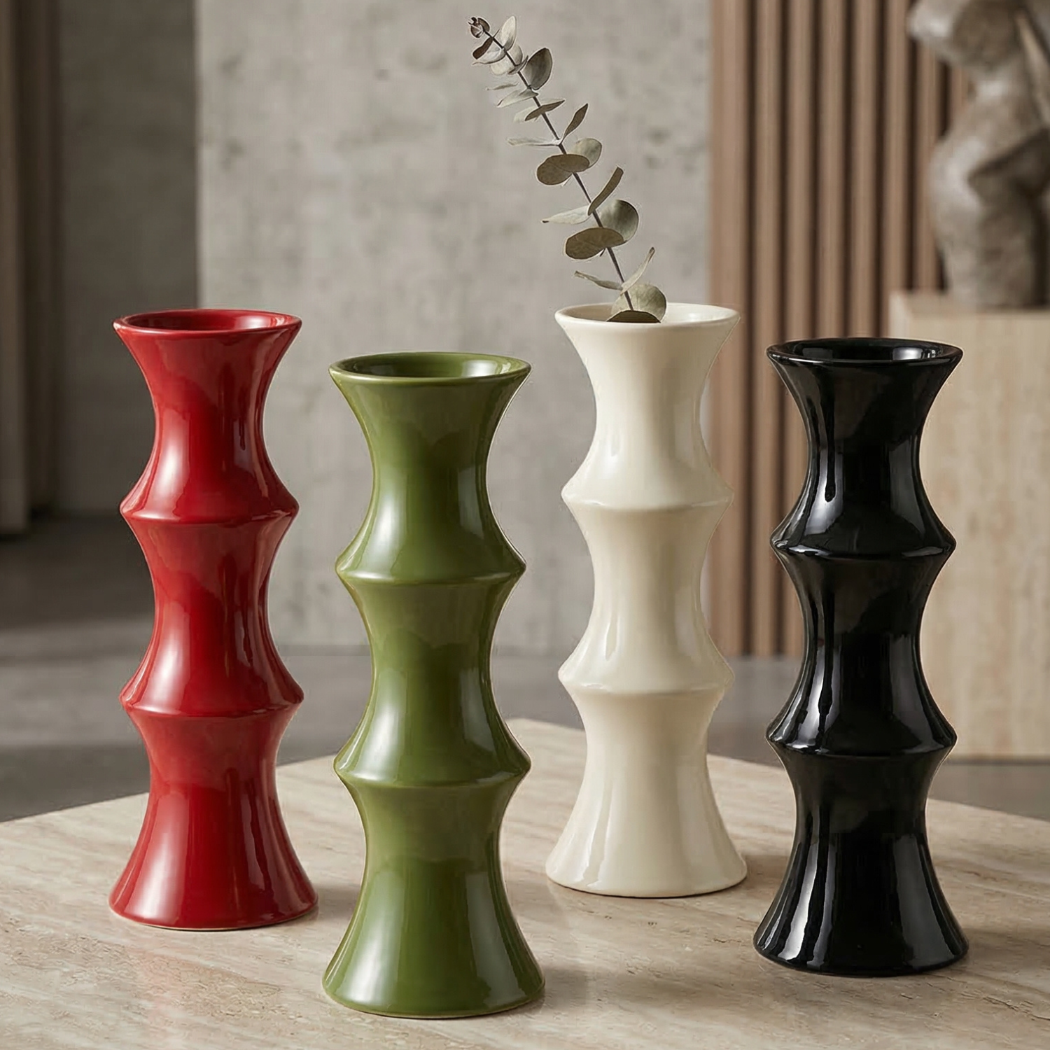 Four cylindrical vases in red, green, white, and black on a wooden surface.