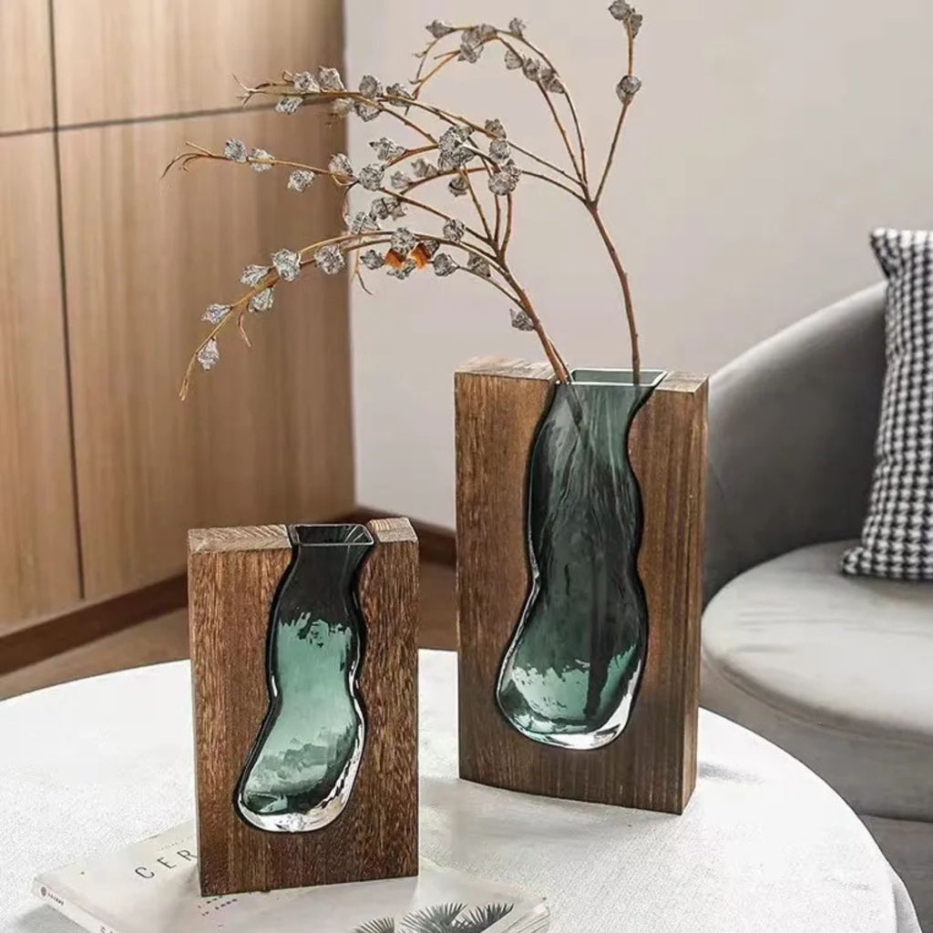 Green glass vase on wood base with branching floral stems