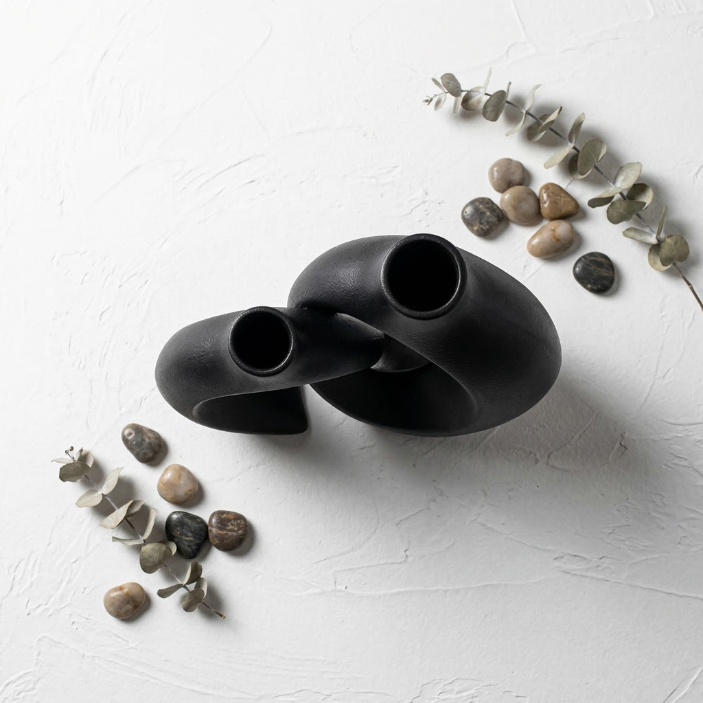 Two dark hollow resin vases with oval cutout openings and matte textured finish