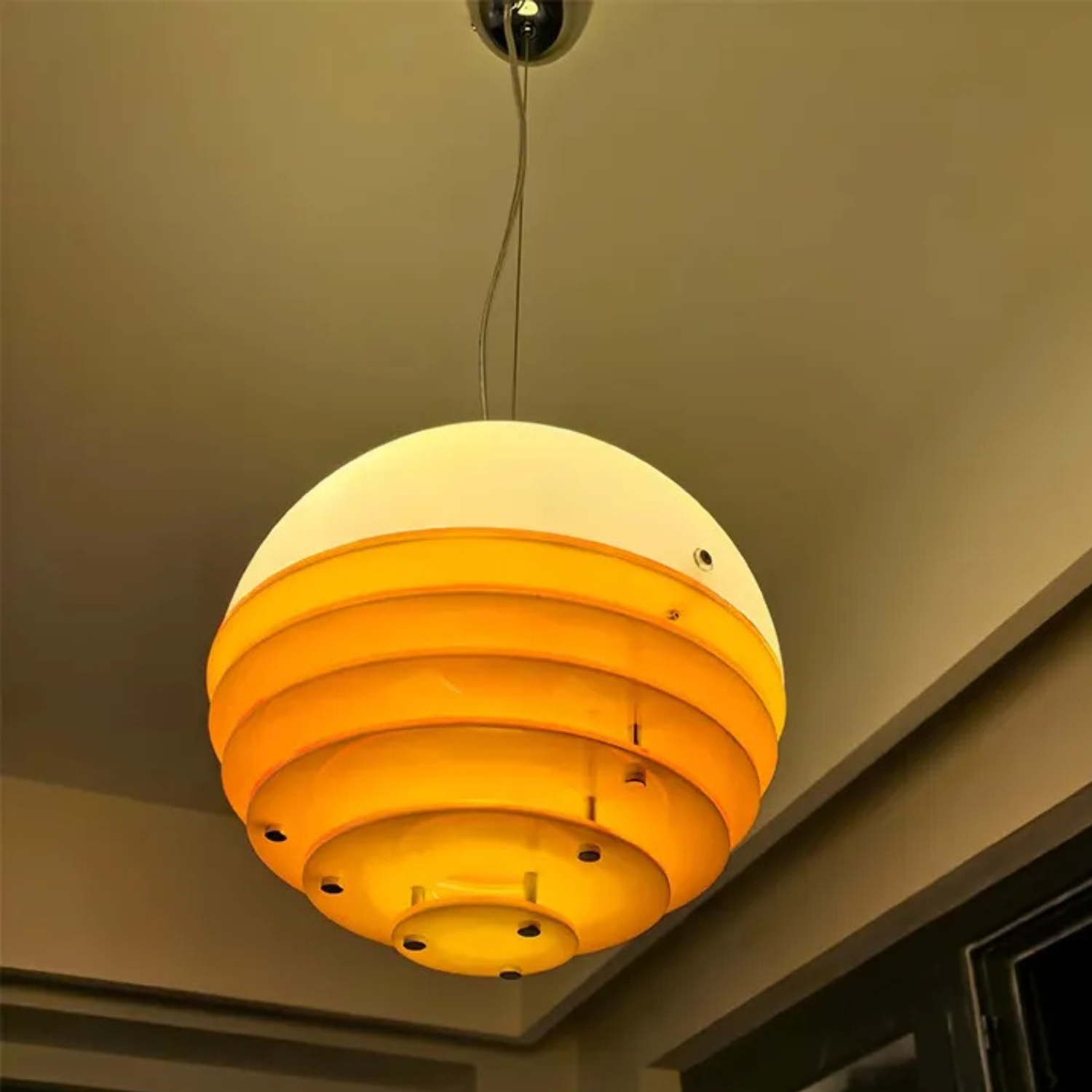 Ceiling light fixture with concentric circular design on a neutral ceiling.