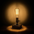 Vintage light bulb on a wooden base with a warm glow against a dark background