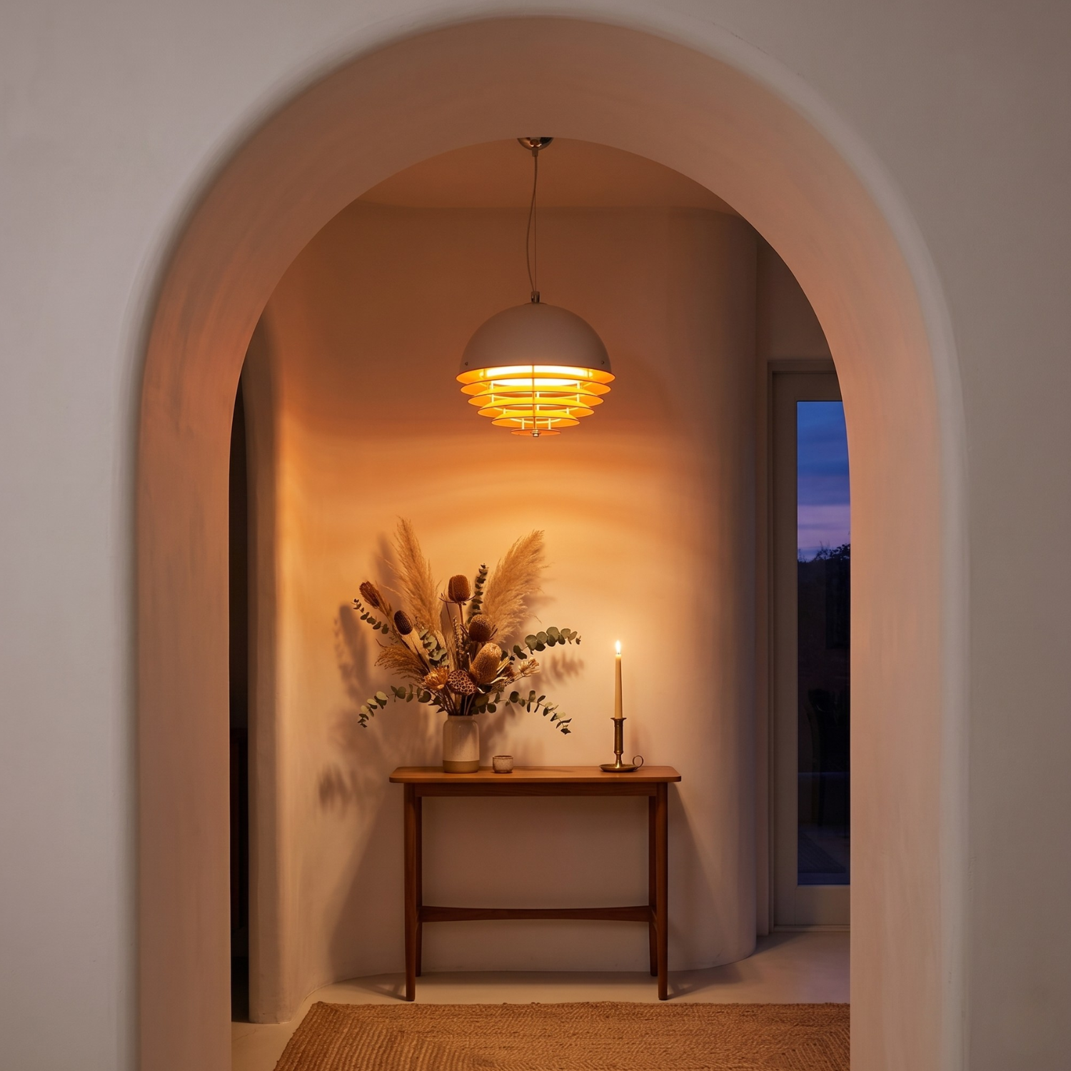 Archway leading to a room with a table, vase of flowers, and candle.