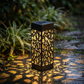 Decorative outdoor light fixture on a wet garden path with plants in the background