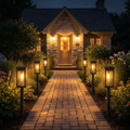 Stone house with a lit pathway and lanterns at night