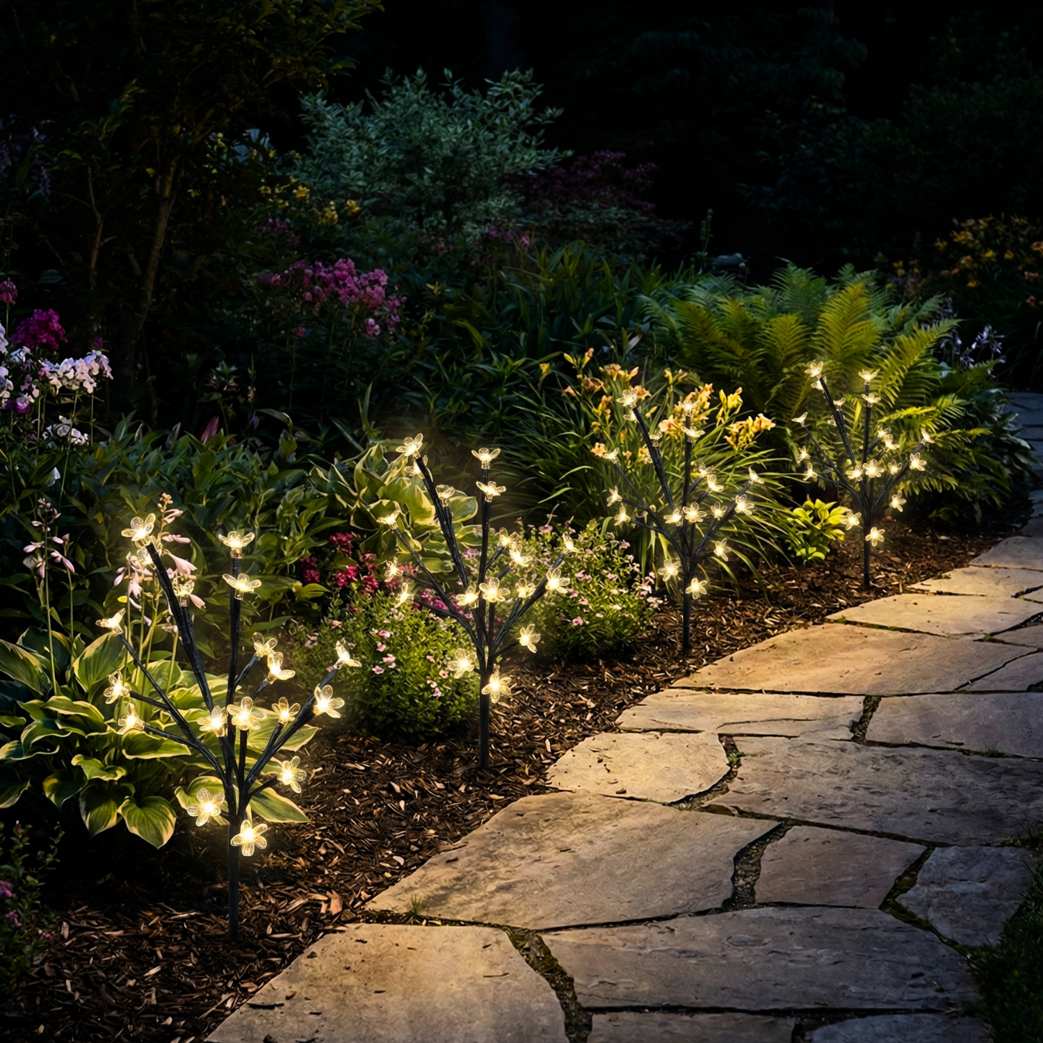 Garden pathway with illuminated plants and a stone walkway at night.