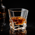 Obsidian cut whiskey tumbler with faceted sides and thick base; filled with amber drink