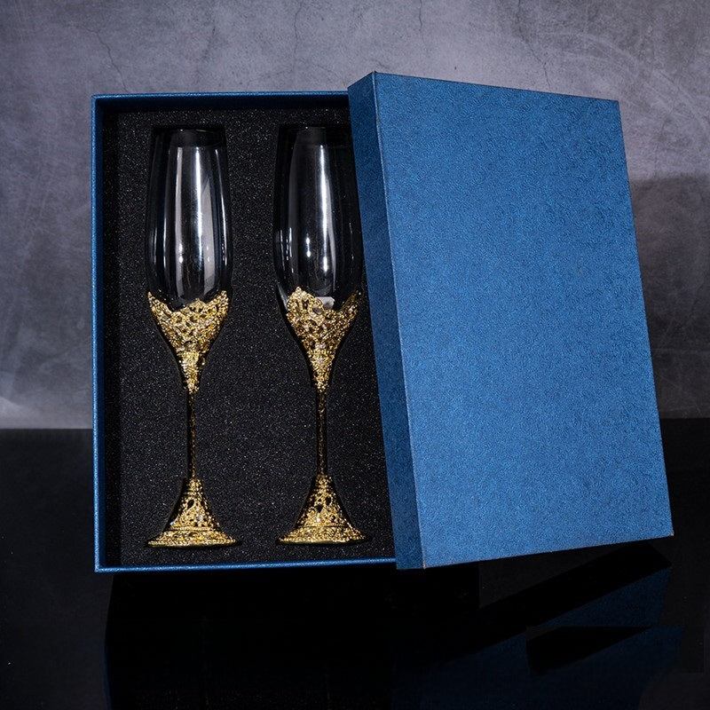 Two gold-embellished wine glasses in a blue box on a dark background