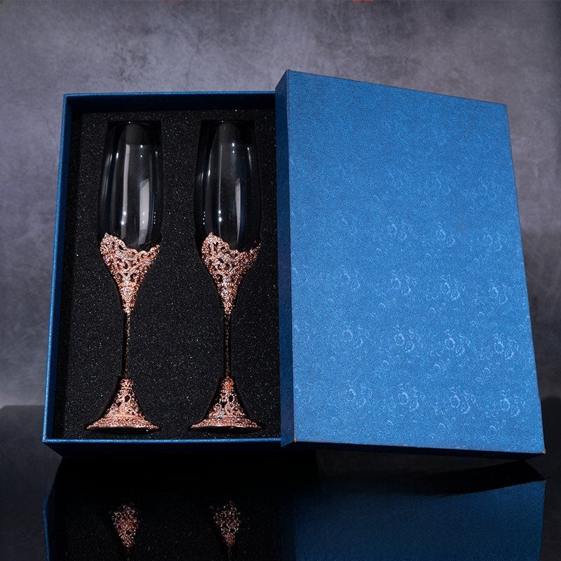 Two decorative champagne flutes in a blue box on a dark background