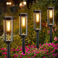 Solar lawn path light stake with warm glowing lantern, black metal frame