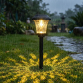 Solar garden light emitting a warm glow on a rainy day with grass and a pathway in the background.