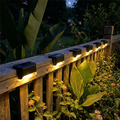 Solar lights on a wooden deck with plants and flowers in the background