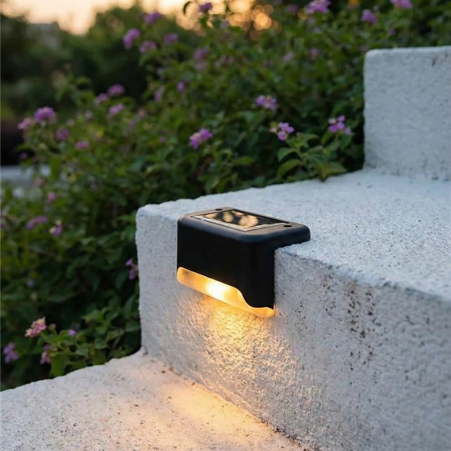 Solar-powered outdoor light fixture on a concrete step with plants in the background