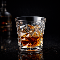 Crystal glass filled with whiskey and ice cubes on a dark background